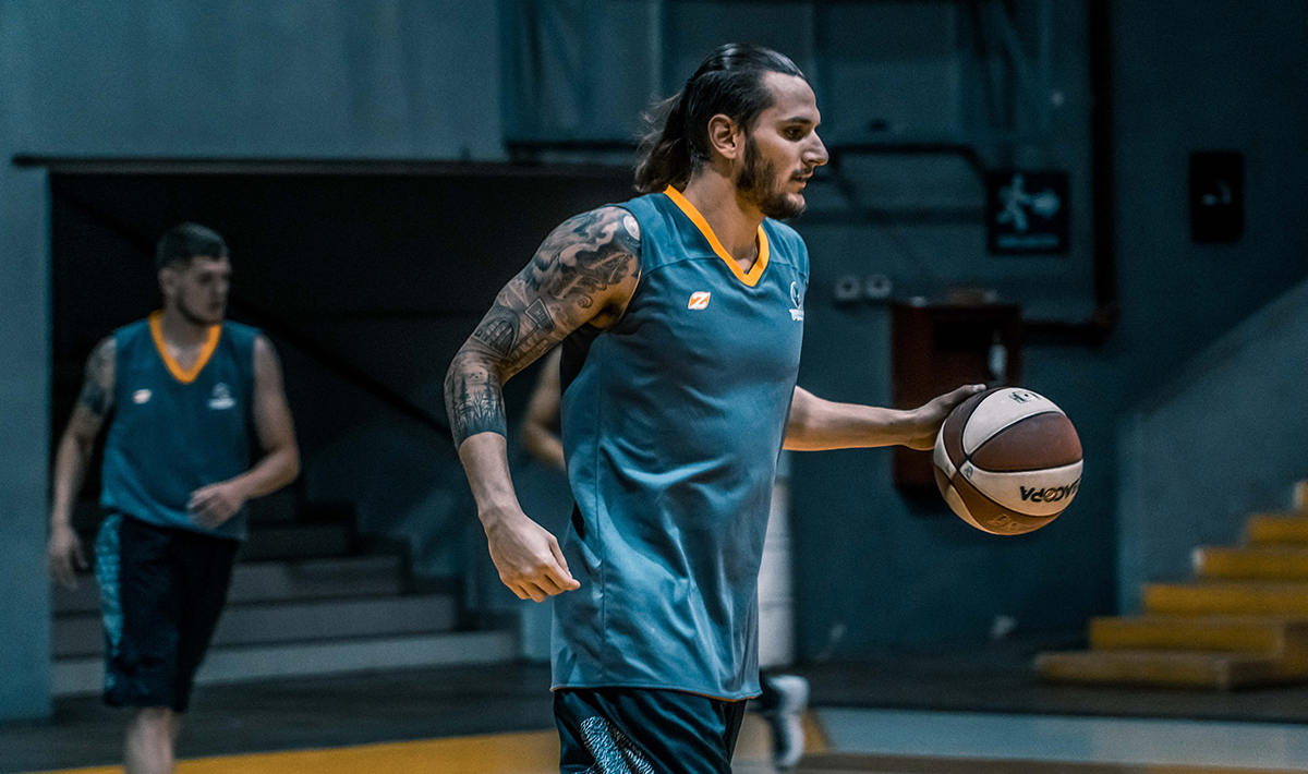Man with tattoos playing basketball.