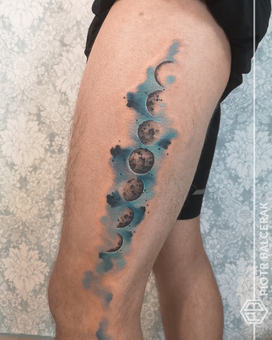 Blue watercolor moon phase tattoo. (Source: @piotr.balcerak.tattoo)
