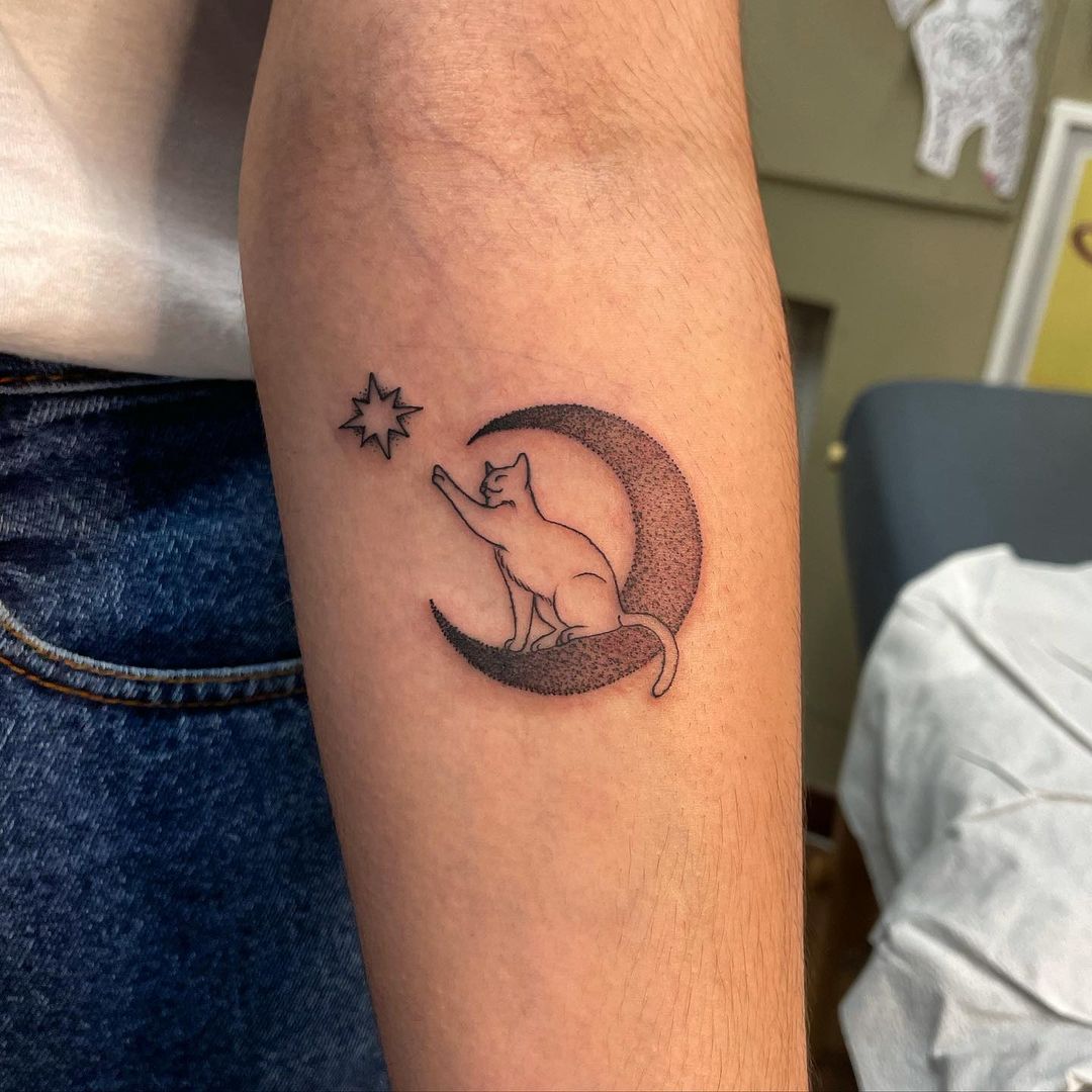 Cat reaching for a star on a crescent moon tattoo. (Source: @lyndzee_)