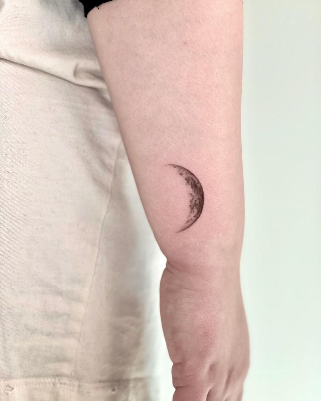 Realistic crescent moon tattoo on arm.